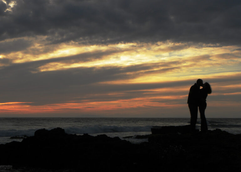 Silhouette romantica di una coppia che si bacia al tramonto, catturata da un fotografo Roma, simbolo di amore eterno e intimità.
